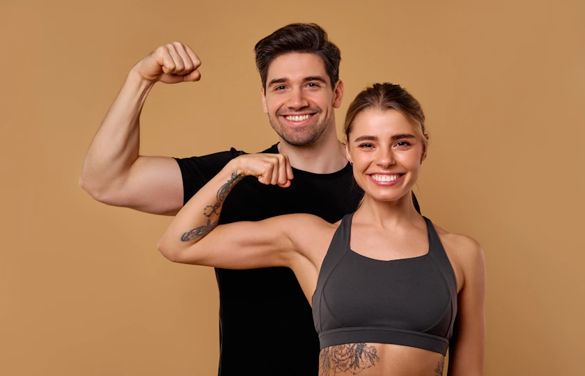 Un ragazzo e una ragazza mostrano i muscoli sorridenti